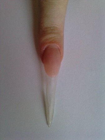 Standardowo przygotowujemy paznokcie. Przezroczystym akrylem przedłużamy je nadając kształt szpica. Na łoże paznokcia nakładamy cover. 